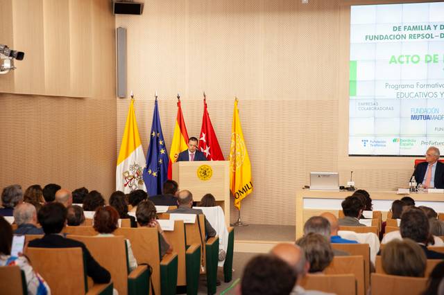 A person giving a speech at a podium in a conference room filled with an audience.