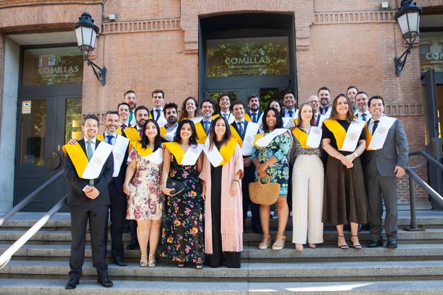 A group of graduates in formal attire celebrating together outside a building.