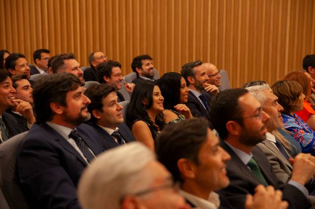 A group of people sitting in a conference room, attentively listening to a speaker.