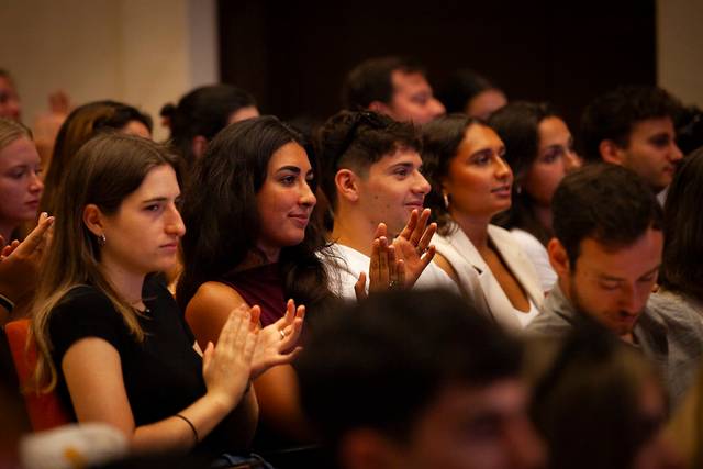 A group of young adults clapping in an auditorium.