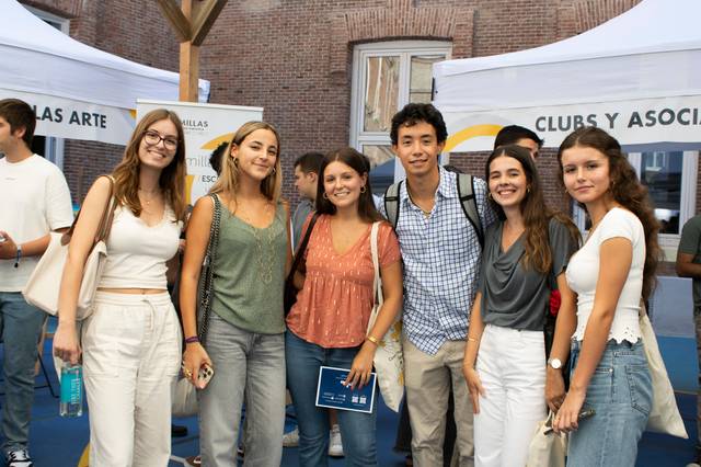 A group of six young adults smiling at a school club fair event.