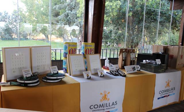 A display of various items on a table at a Comillas University event.