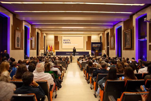 An audience attentively listening at a conference in a large hall.