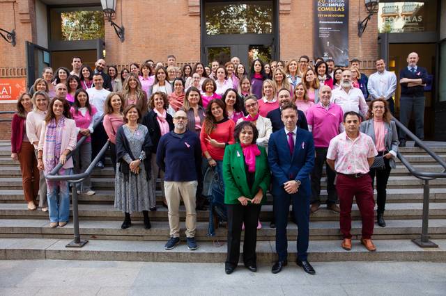 A large group of individuals of various ages and genders posing for a photo on some steps outside a building.