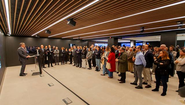 A man is giving a speech to a large group of people in a modern conference room.