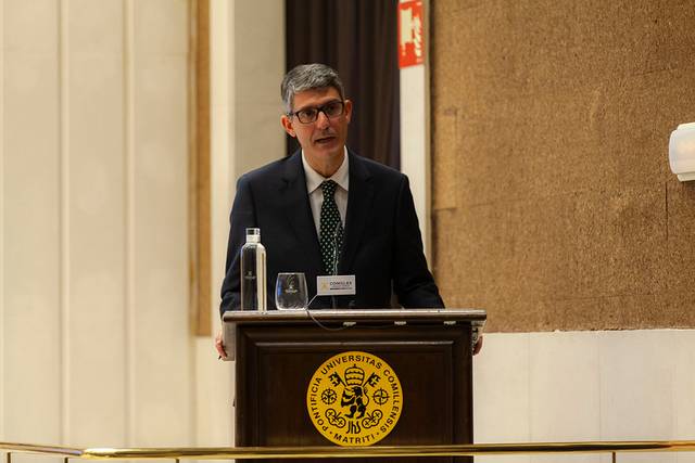 Un hombre da un discurso en un podio con el emblema de una universidad.