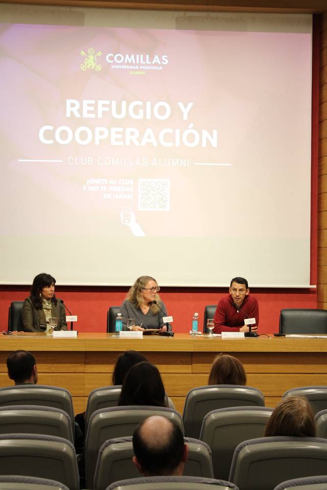 Tres personas sentadas en el podio de una sala de conferencias durante un evento titulado 'Refugio y Cooperación', organizado por el Club Comillas Alumni.