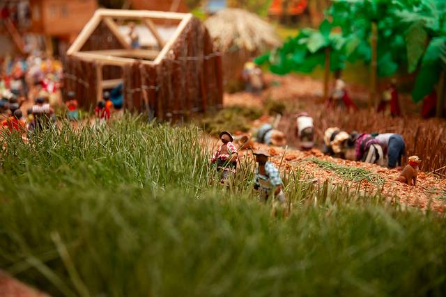 Maqueta detallada que representa un entorno rural con figuras humanas en diversas actividades agrícolas.