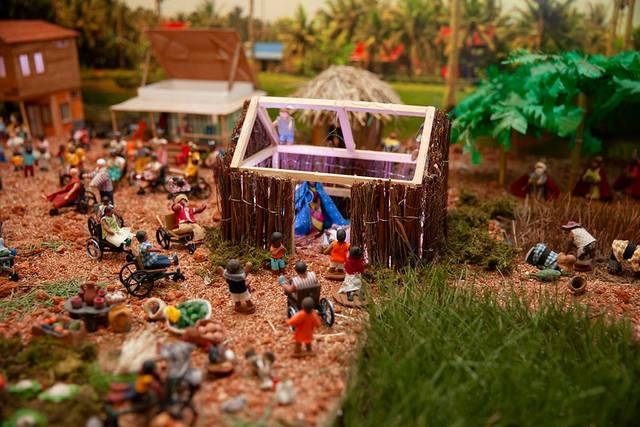 Maqueta detallada de una escena de mercado al aire libre con figuras en miniatura realizando diversas actividades.