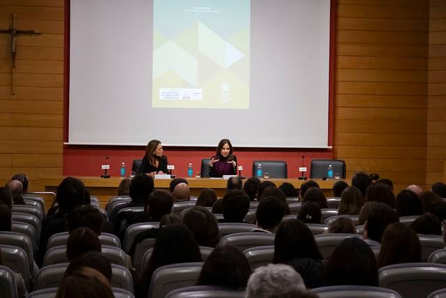 Dos personas están presentando en un auditorio frente a una audiencia.