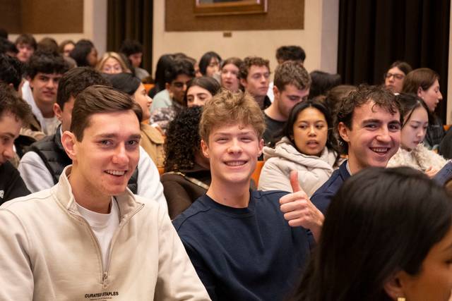 Grupo de jóvenes sonriendo y participando en un evento en un auditorio.