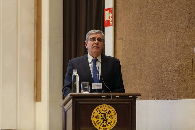 Un hombre hablando en un podio con el escudo de la Universidad de Salamanca al frente.