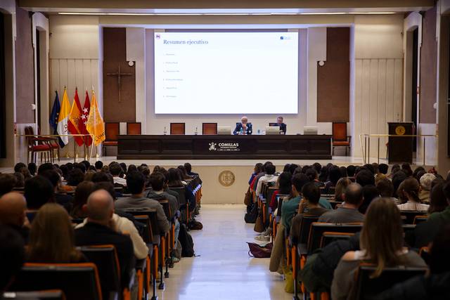 Dos personas están dando una conferencia en un auditorio lleno de público.