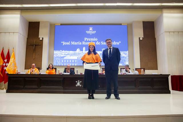 Una persona recibiendo un premio durante una ceremonia en un auditorio, con otras personas sentadas al fondo.