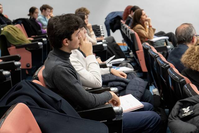 Un grupo de personas sentadas en un auditorio prestando atención a una presentación.