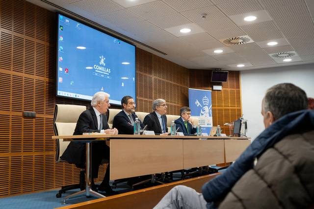 Cuatro personas sentadas frente a un ordenador en una sala de conferencias.