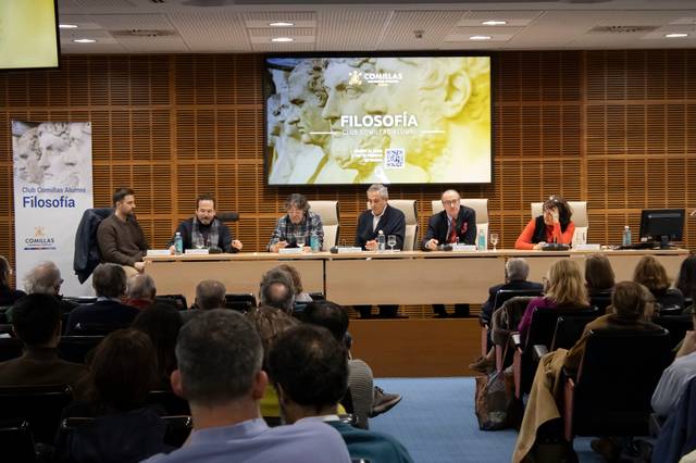 Un grupo de personas discutiendo sobre temas filosóficos en un evento académicos.