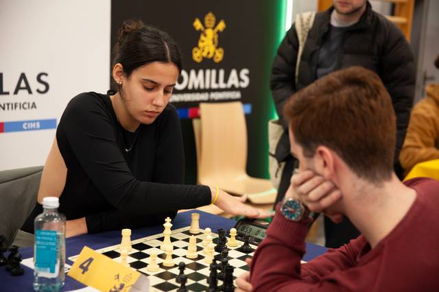 Una joven jugadora de ajedrez se concentra en una partida mientras su oponente la observa.