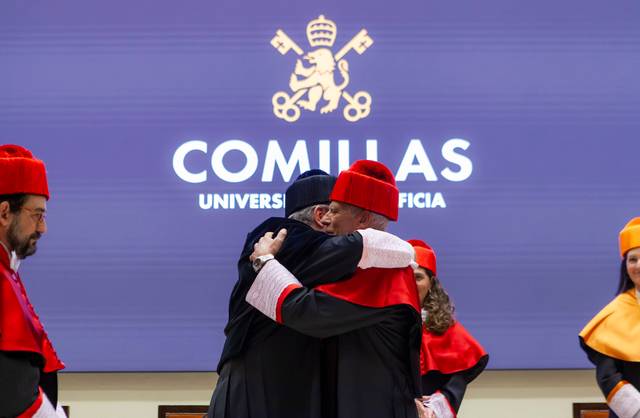 Un grupo de personas se abrazan en una ceremonia en la Universidad de Comillas.