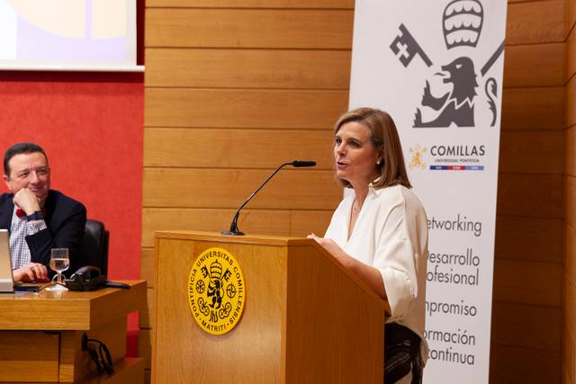 Una mujer está hablando en un podio durante un evento en una sala de conferencias.