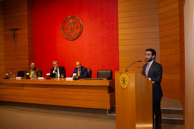 Un hombre habla en un podio frente a un grupo de personas sentadas en un panel.