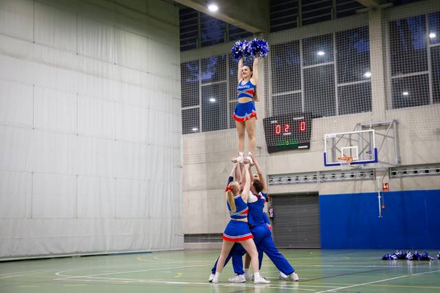 Un grupo de animadoras realizando una pirámide en un gimnasio.