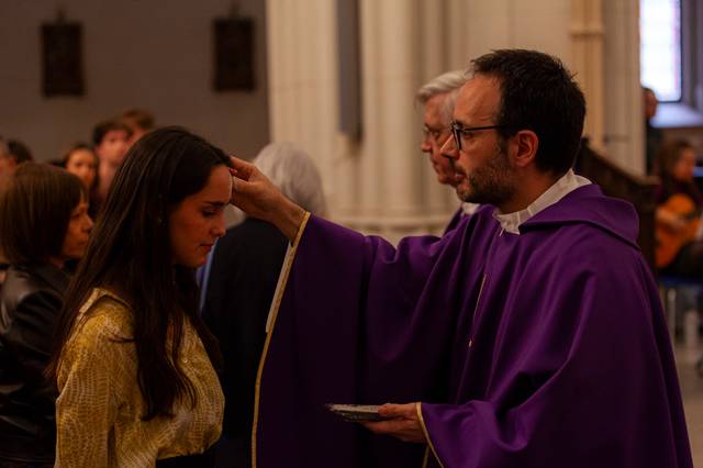 Un sacerdote aplica una unción a una mujer en un ambiente religioso durante una ceremonia.