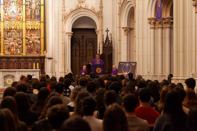 Una ceremonia religiosa en una iglesia con un grupo de personas reunidas y un orador en el altar.