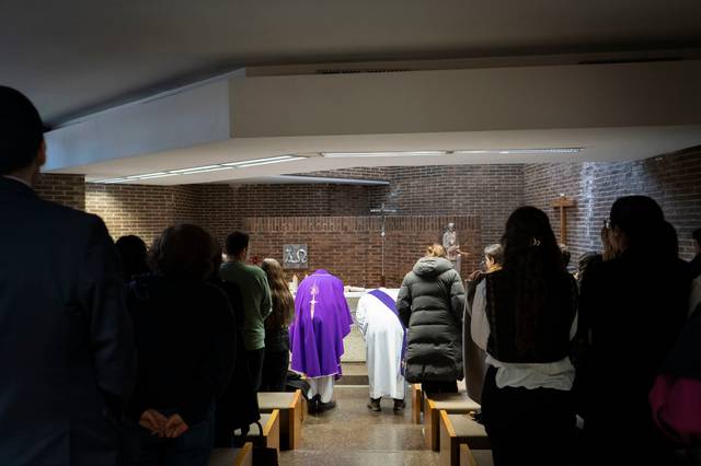 Una ceremonia religiosa se lleva a cabo en un ambiente sobrio con asistencia de varias personas.