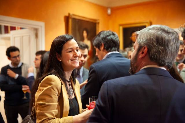 Una mujer sonriente conversa en una reunión social en un ambiente elegante.