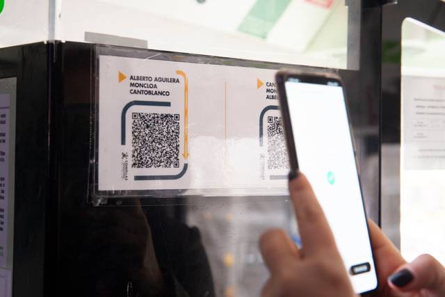 Una persona escaneando un código QR en un cartel informativo.