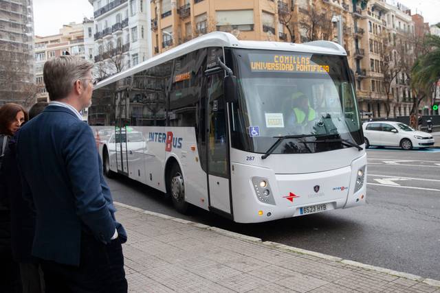 Un autobús de InterBus se detiene en una parada mientras un hombre observa.