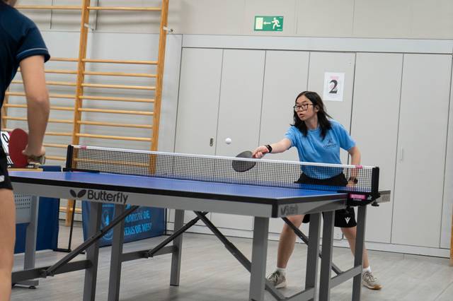 Una jugadora de tenis de mesa está a punto de golpear la pelota con su raqueta.