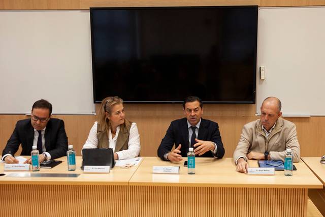 Un grupo de personas discutiendo en una reunión frente a una pantalla.