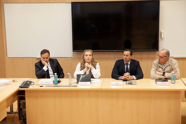 Cuatro personas sentadas en una mesa durante una presentación o reunión.