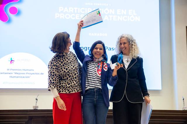 Tres mujeres celebran un premio durante un evento de reconocimiento.