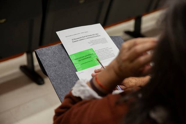 Una persona sostiene un documento en una reunión mientras toca su cabello.