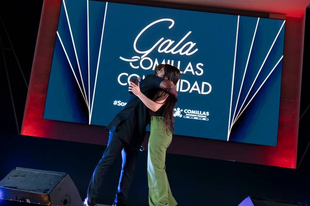 Una pareja se abraza en el escenario de un evento llamado Gala Comillas Comunión.