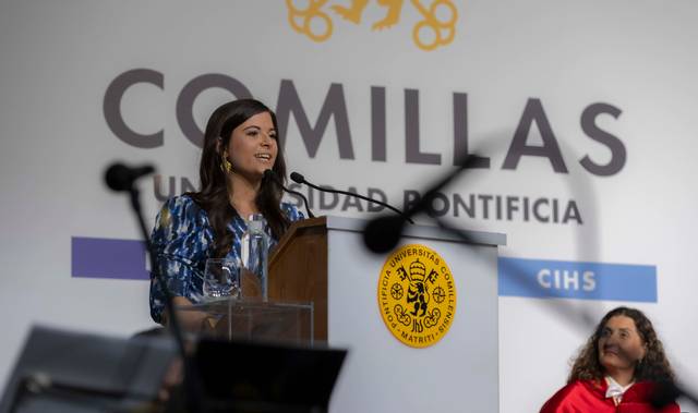 Una mujer se encuentra en el podio de una ceremonia, pronunciando un discurso frente a un público.