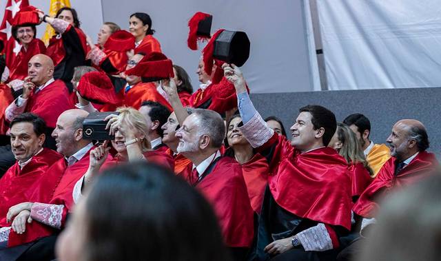 Un grupo de personas vestidas con togas rojas y birretes celebra un evento solemne.