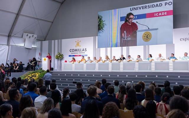 Una ceremonia académica en la Universidad Pontificia Comillas con un escenario y un público atento.