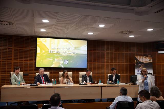 Un panel de discusión sobre movilidad y seguridad vial con varios ponentes en un auditorio.