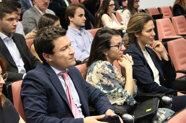 Un grupo de personas escucha atentamente en un auditorio.