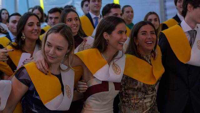 Un grupo de graduados celebrando su ceremonia con togas y sashes amarillos.