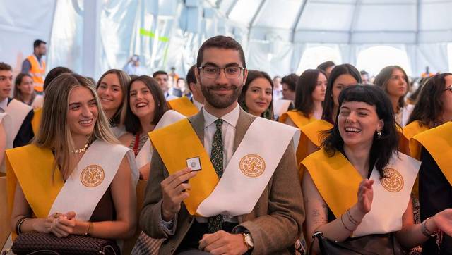 Un grupo de estudiantes sonrientes en una ceremonia de graduación, con togas y birretes.