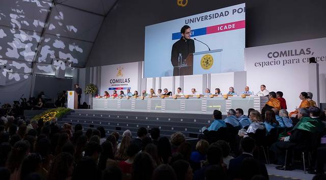 Un evento de graduación en la Universidad Pontificia Comillas con un orador en el escenario frente a una audiencia.