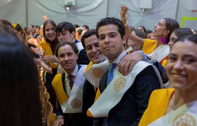 Un grupo de graduados sonríen y celebran en una ceremonia de graduación.
