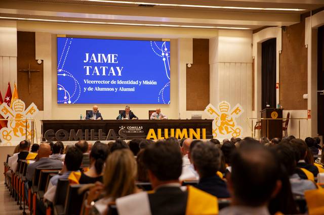 Un evento en una sala con un panel de oradores frente a una audiencia.