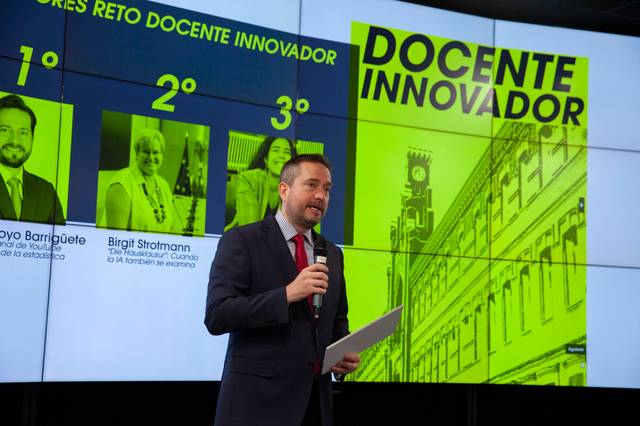 Un presentador habla sobre los ganadores de un reto docente innovador en una pantalla grande.