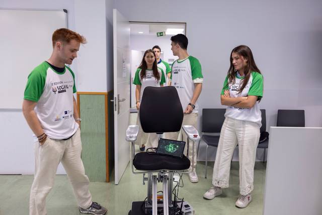 Un grupo de jóvenes observa un dispositivo tecnológico en una sala de presentación.
